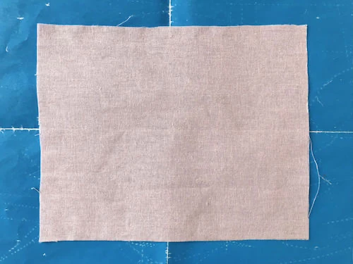 Pink cotton fabric placed on blue dressmakers tracing paper.