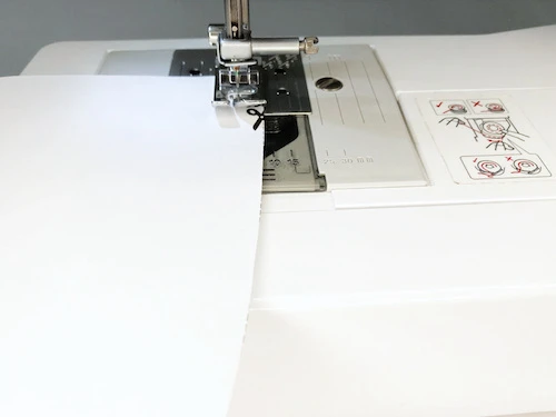 Sewing an inner curved seam on a sewing practice sheet.