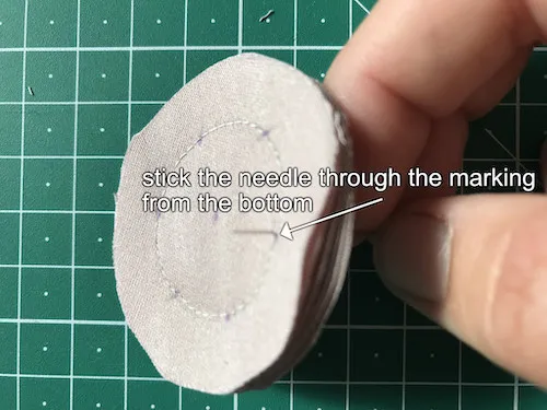 Stick the needle to the fabric stack from the bottom passing through one of the petal markings.