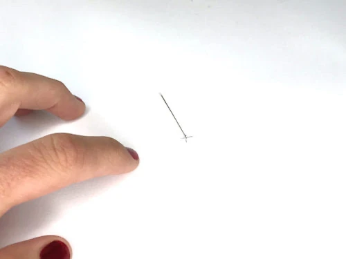 A pin sticked into a paper that will make a center of a full circle.